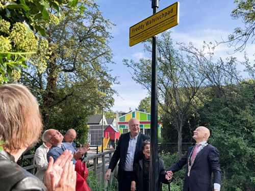 Straatnamencommissie bij een straatnaambord