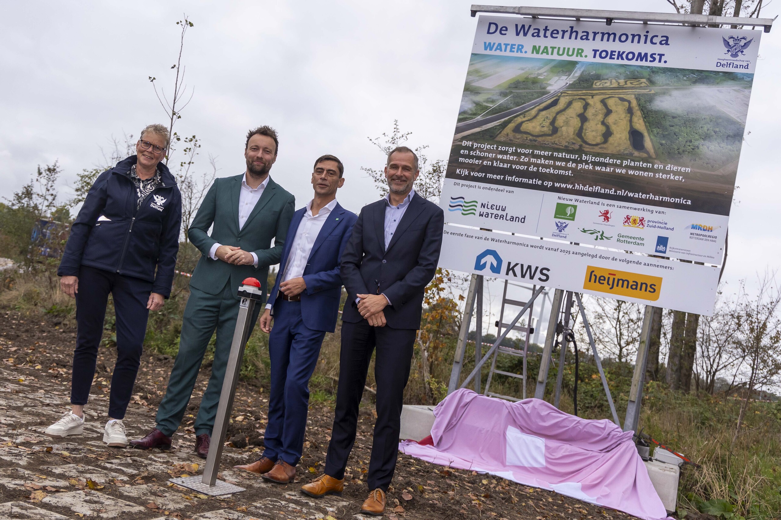 Foto van de bestuurders bij het bouwbord van de Waterharmonica
